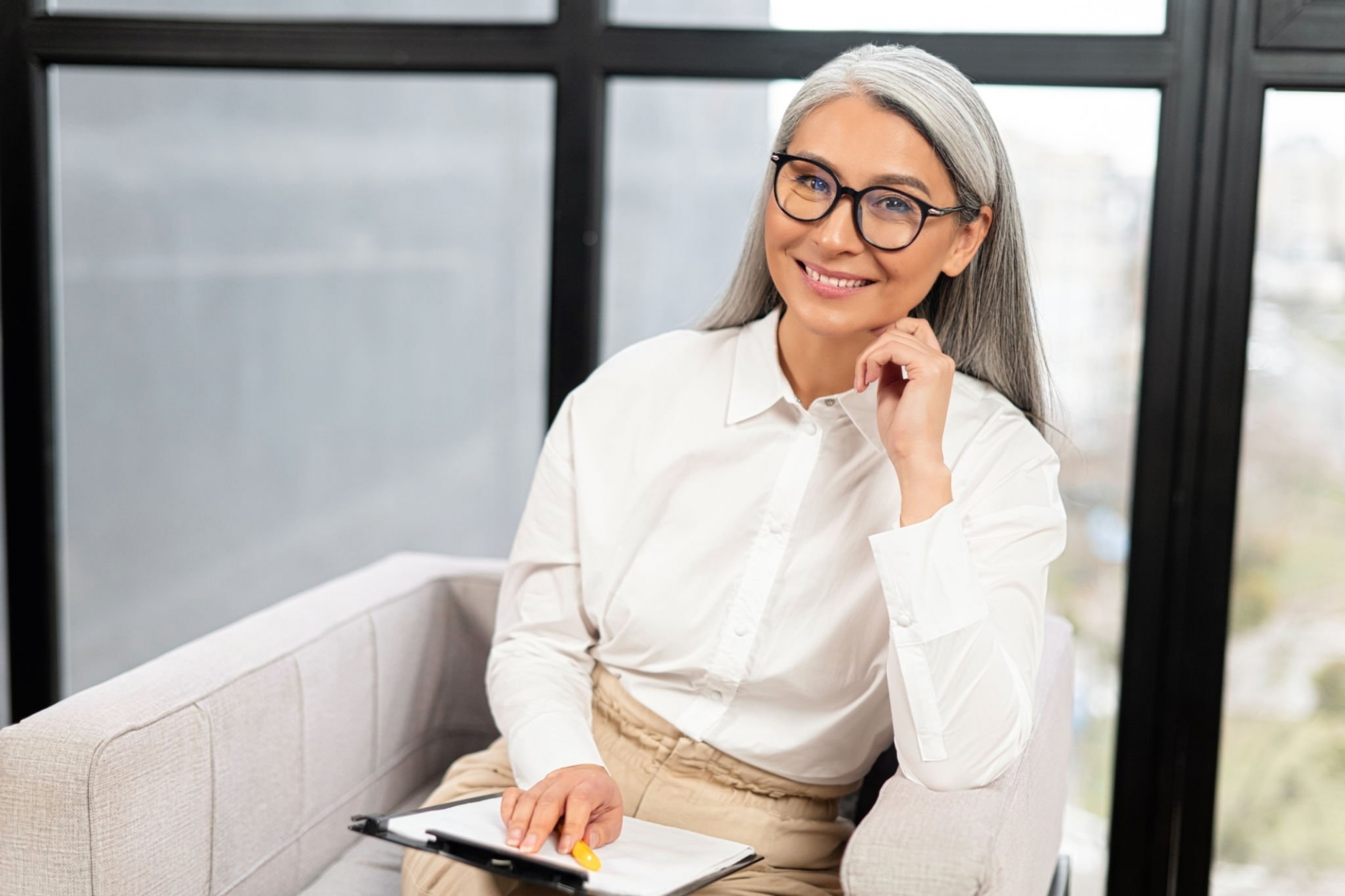 platinum blonde middle age woman in a crispy white shirt sitting and smiling